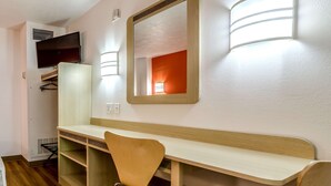 A room with a wooden desk, a chair, a mirror, and a television mounted on the wall. - Motel 6 Kearney, NE (Kearney)