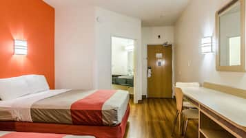Et hotelværelse med to senge, et skrivebord og et spejl.