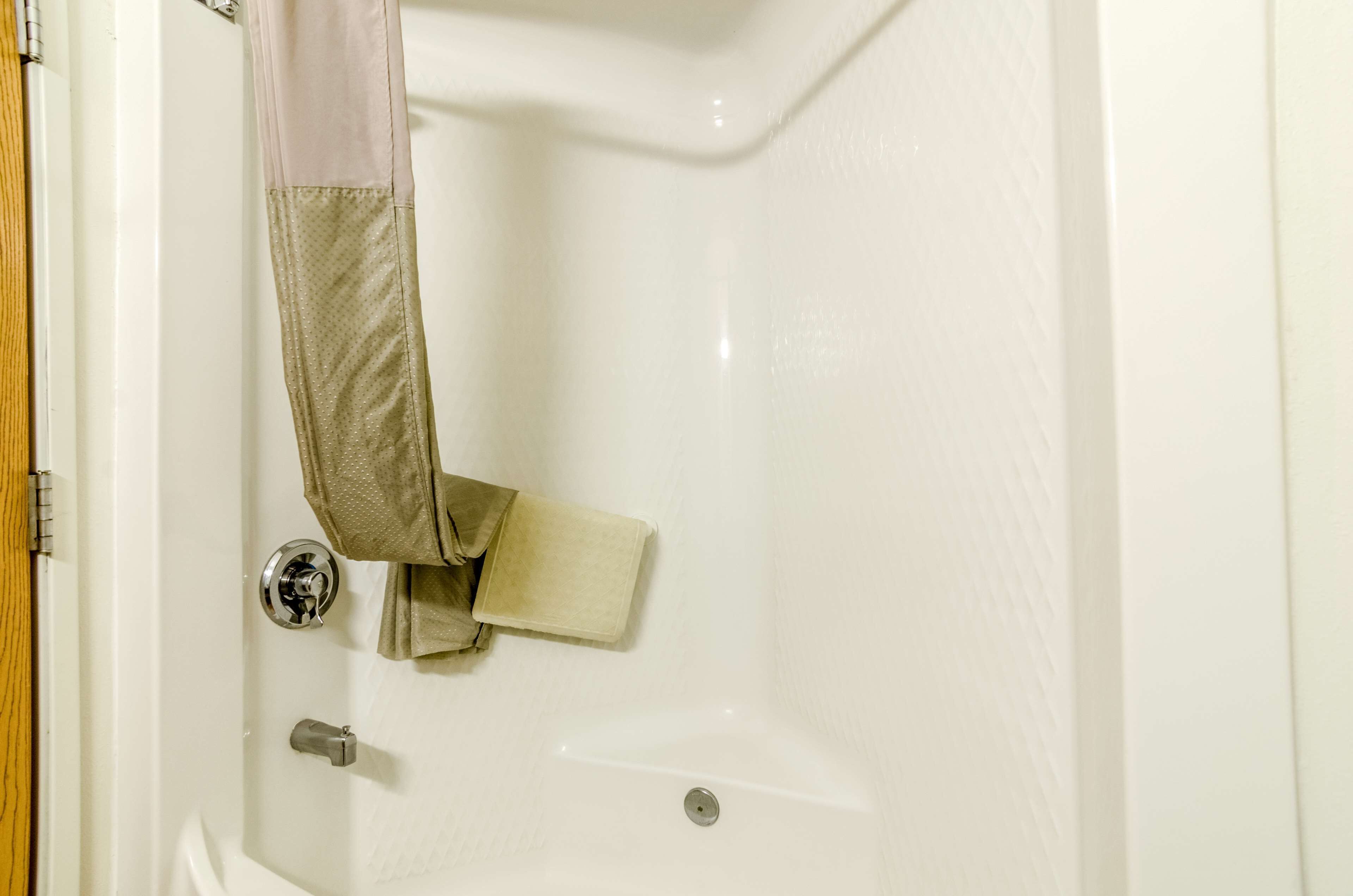 A white bathtub with a shower curtain, a towel, and a toilet paper holder.