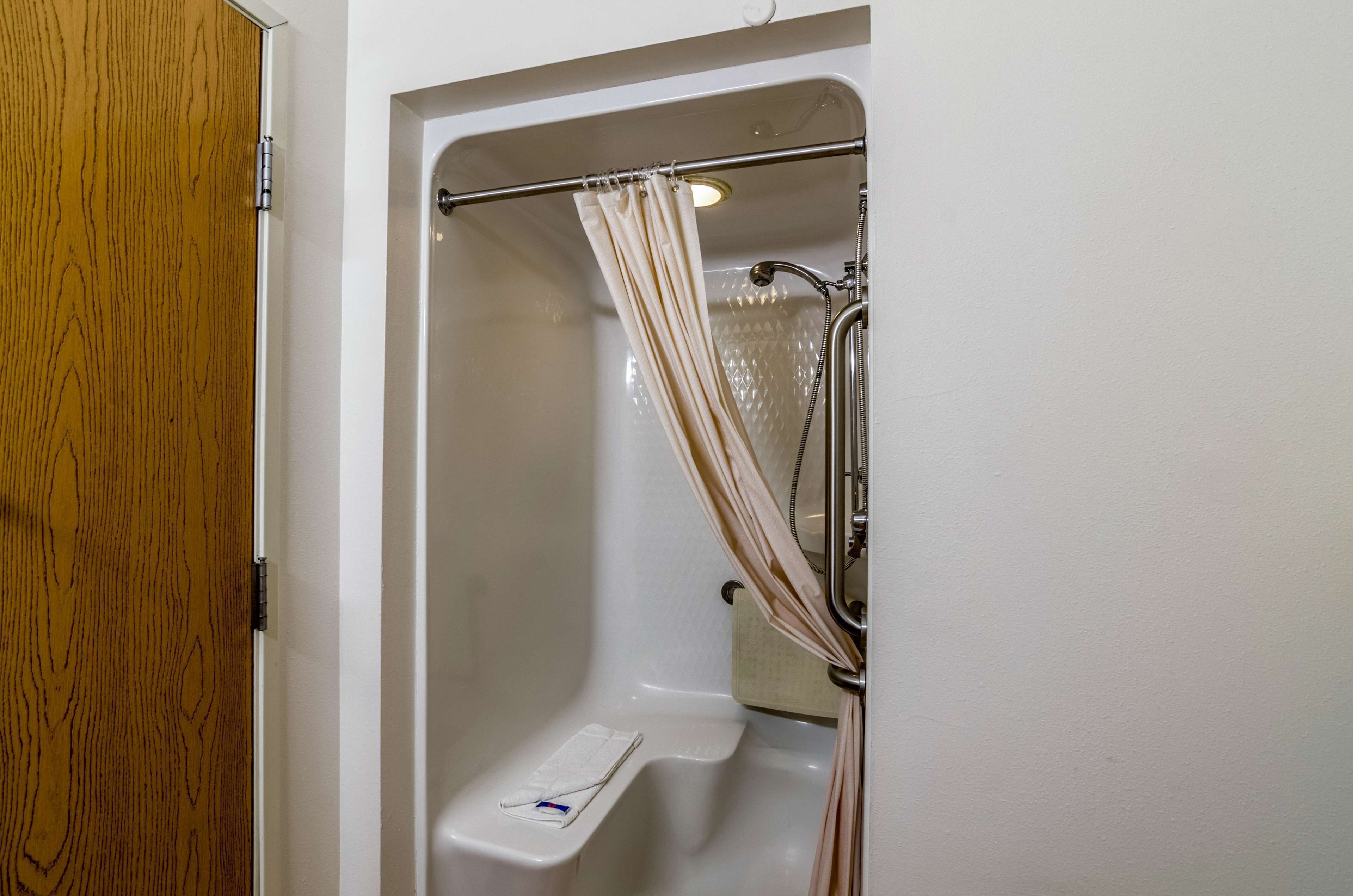 Une salle de bain avec une porte en bois, une baignoire, un rideau de douche et un porte-serviettes.