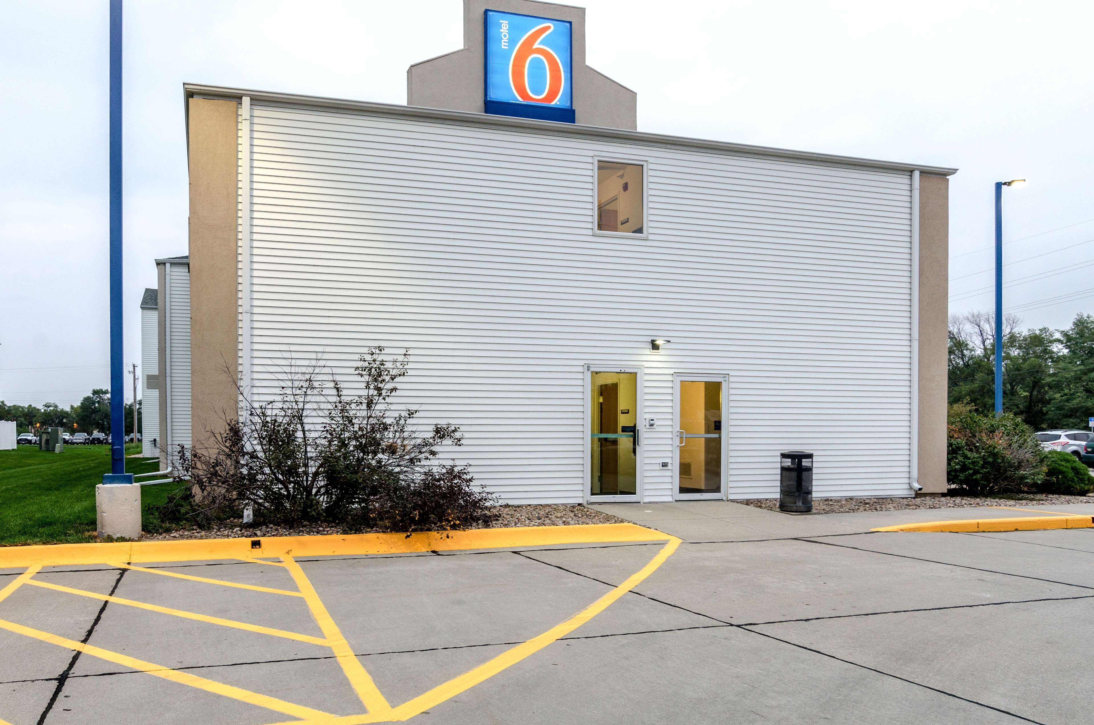 A motel with a '6' sign, a single entrance, and a parking lot with marked spaces.