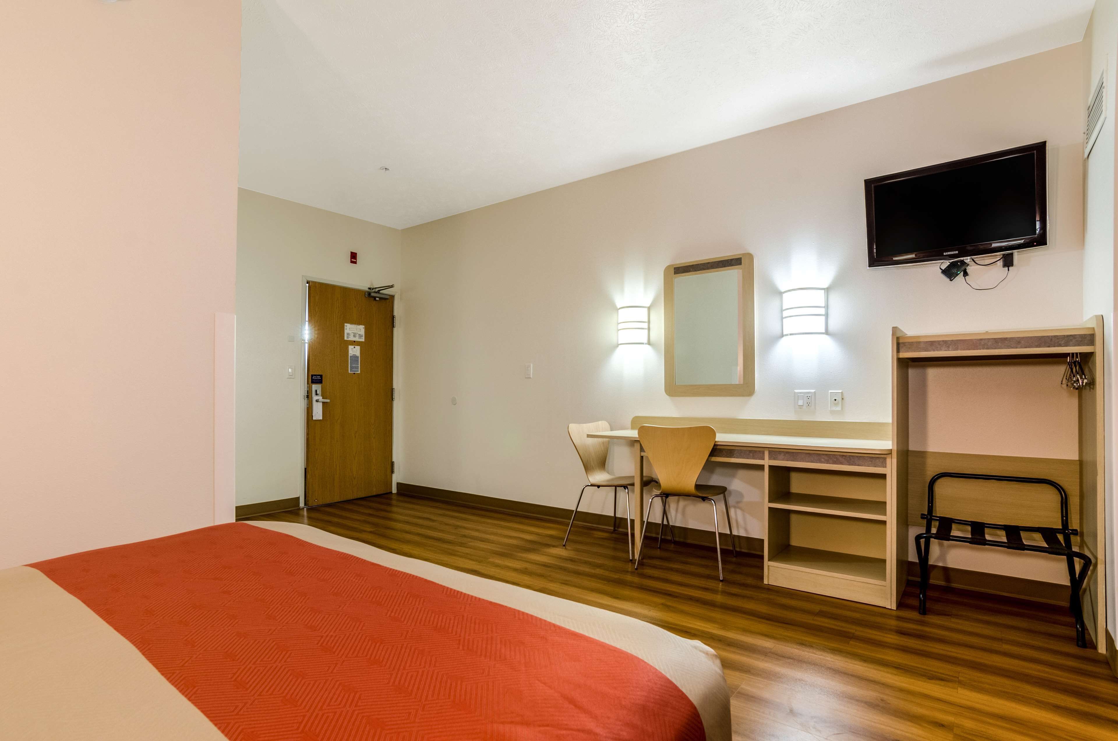 A hotel room with a bed, a desk, a chair, a TV, and a fireplace.