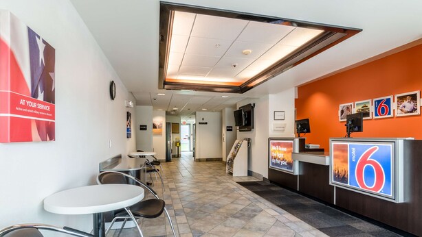 A hotel lobby with a reception desk, seating area, and a staircase leading to other floors. - Motel 6 Kearney, NE (Kearney)