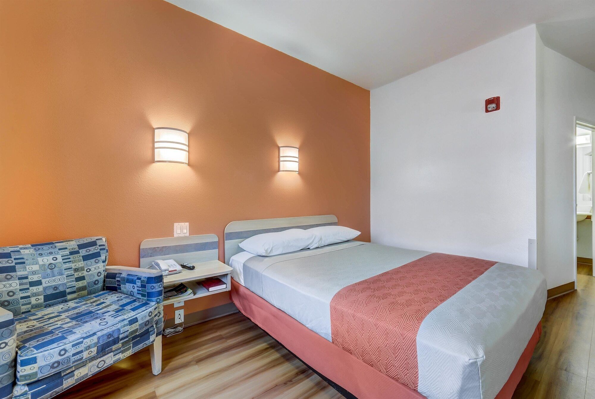 A hotel room with a bed, a desk, and a chair.