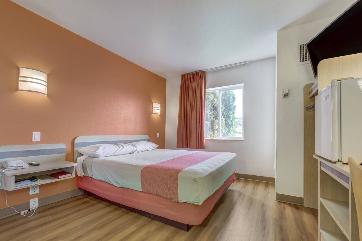 Une chambre d’hôtel équipée d’un lit, d’une table de chevet, d’une lampe, d’une fenêtre et d’un téléviseur intégré.