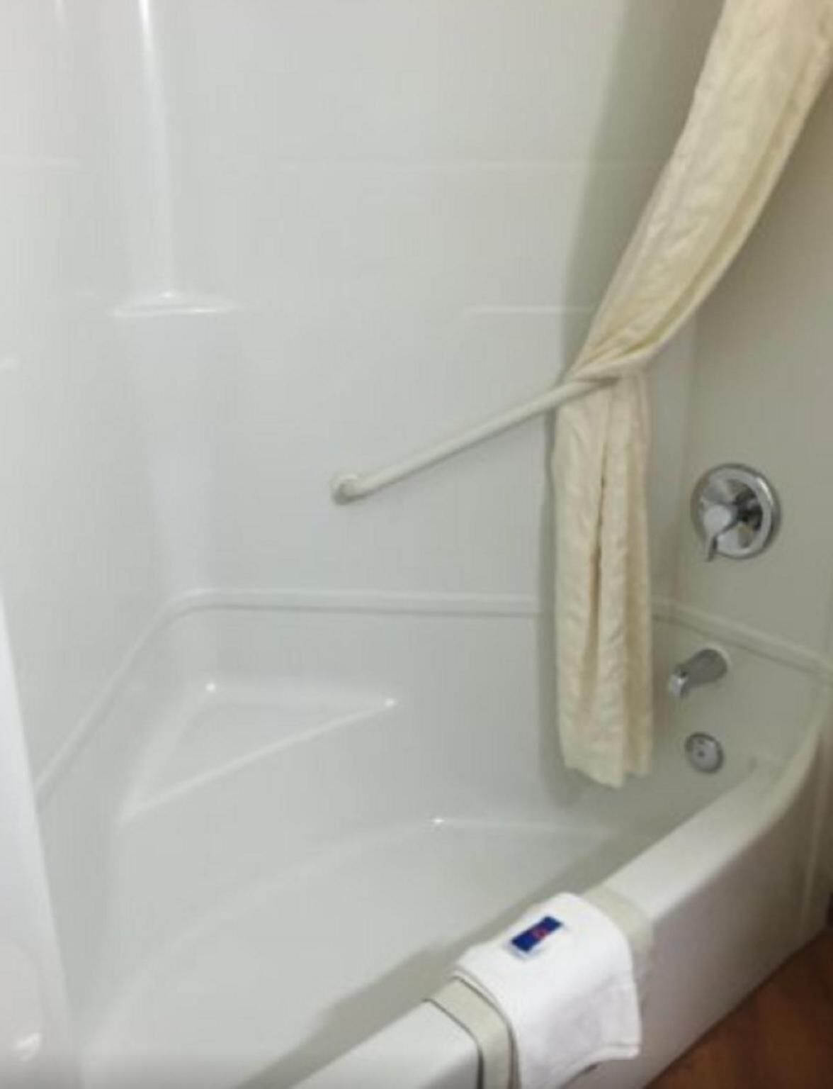 Une baignoire blanche avec un rideau de douche, une serviette et un robinet.