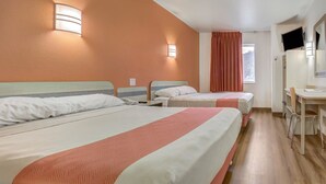 Ein Hotelzimmer mit zwei Betten, einem Schreibtisch, einem Stuhl und einem Fernseher.
