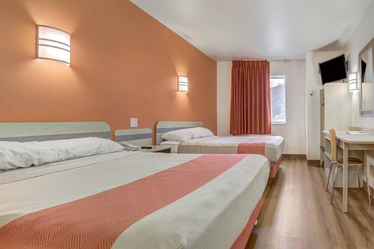 Une chambre d’hôtel avec deux lits, un bureau, une chaise et un téléviseur.
