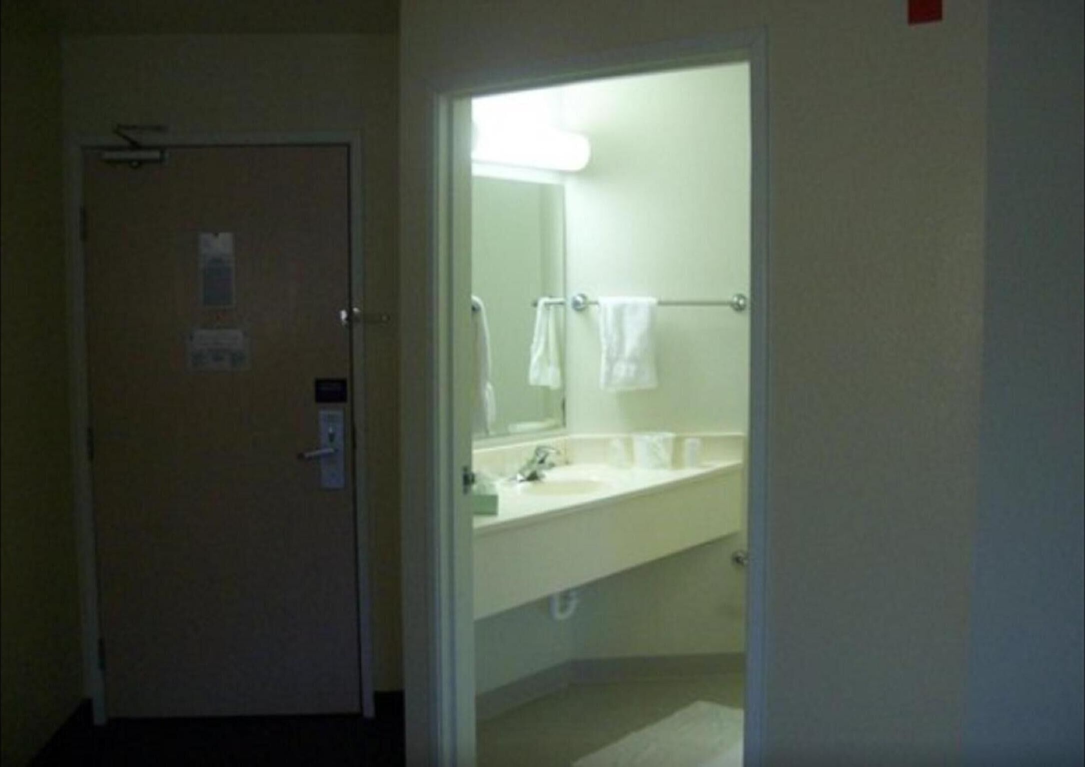 A hotel bathroom with a sink, mirror, and towel rack.