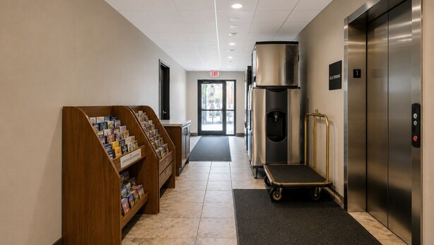 A hallway with a wooden information kiosk, an elevator, and a water dispenser. - Econo Lodge Menomonie (Menomonie)