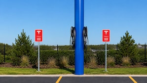 A parking area with electric vehicle charging stations, marked by red signs, and a blue pole in the center. - Econo Lodge Menomonie (Menomonie)