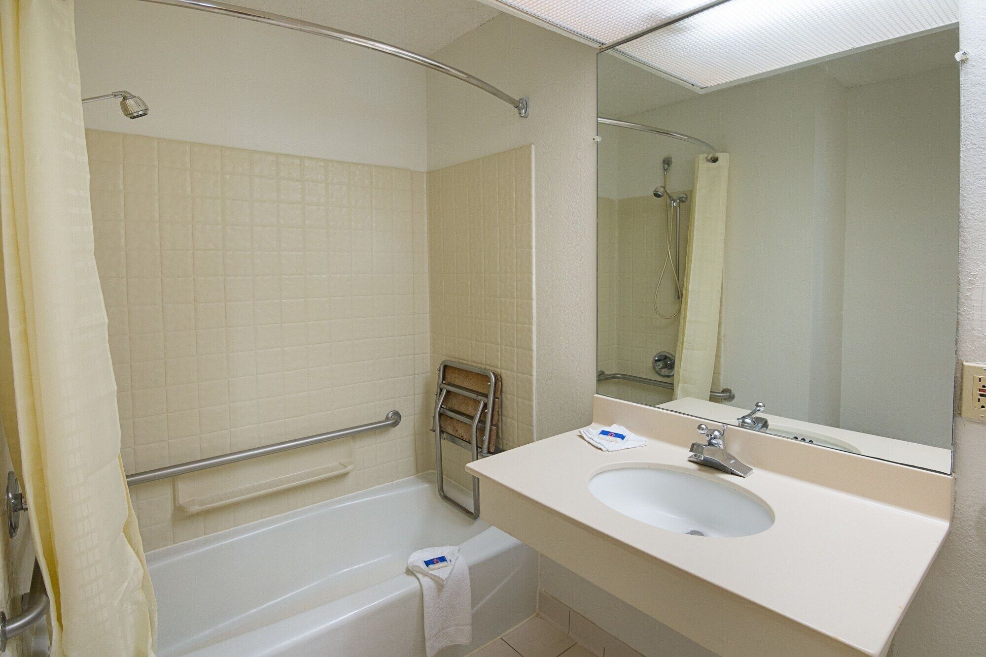 A bathroom with a bathtub, a sink, a mirror, and a shower curtain.