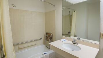 A bathroom with a bathtub, a sink, a mirror, and a shower curtain.