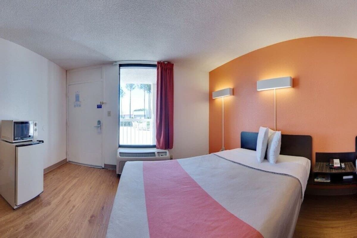 A hotel room with two beds, a TV, a small table, and a bathroom visible through an open door.