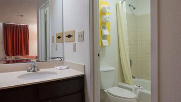 A bathroom with a sink, mirror, toilet, and shower.