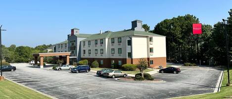 A multi-story hotel with a parking lot, a covered entrance, and a sign indicating a Ramada Inn.