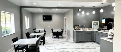 Una cocina moderna con suelo de mármol, una isla integrada y un televisor de pantalla plana montado sobre la isla.