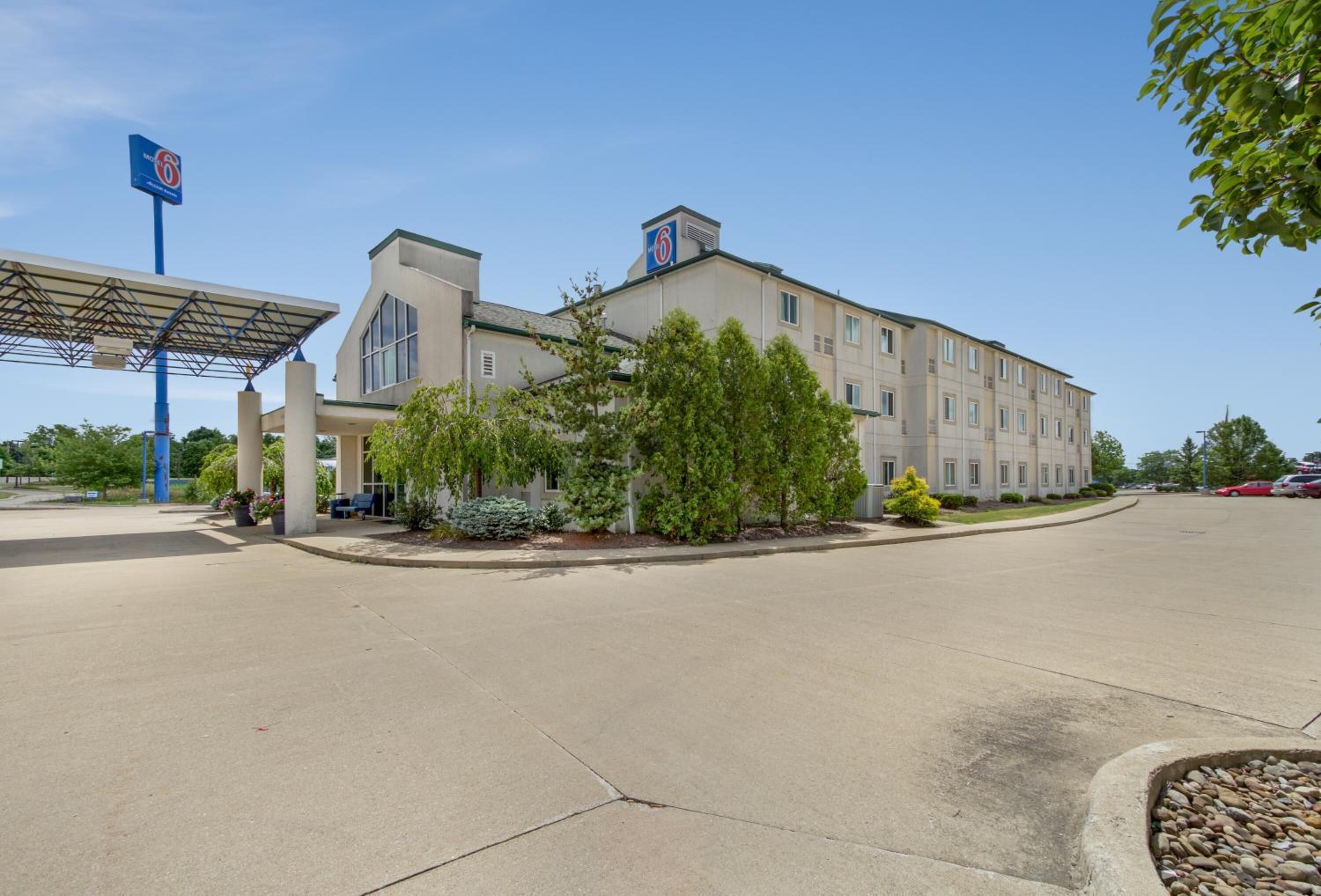 A hotel with a large parking lot, a gas station, and a covered outdoor seating area.