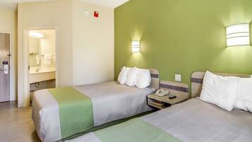 Een hotelkamer met twee bedden, een badkamer en een groene accentmuur.