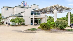 A hotel with a covered entrance, a parking lot, and landscaped areas with shrubs and a small tree. - Motel 6 Medina, OH - Cleveland (Medina)