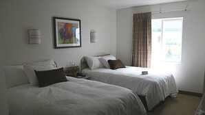 A hotel room with two beds, a painting on the wall, and a window with curtains. - Buffalo Inn (Buffalo)