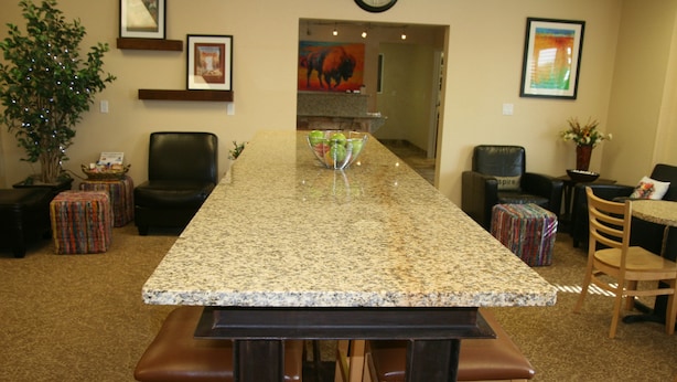 A kitchen with a granite countertop, wooden stools, and a dining table. - Buffalo Inn (Buffalo)