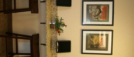 A reception area with a counter, framed pictures, a small plant, and a wooden chair.