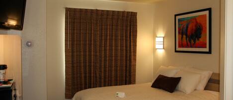Una habitación de hotel con una cama, un escritorio, una lámpara y un cuadro en la pared.