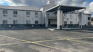 A multi-story building with a covered parking area and a bench.