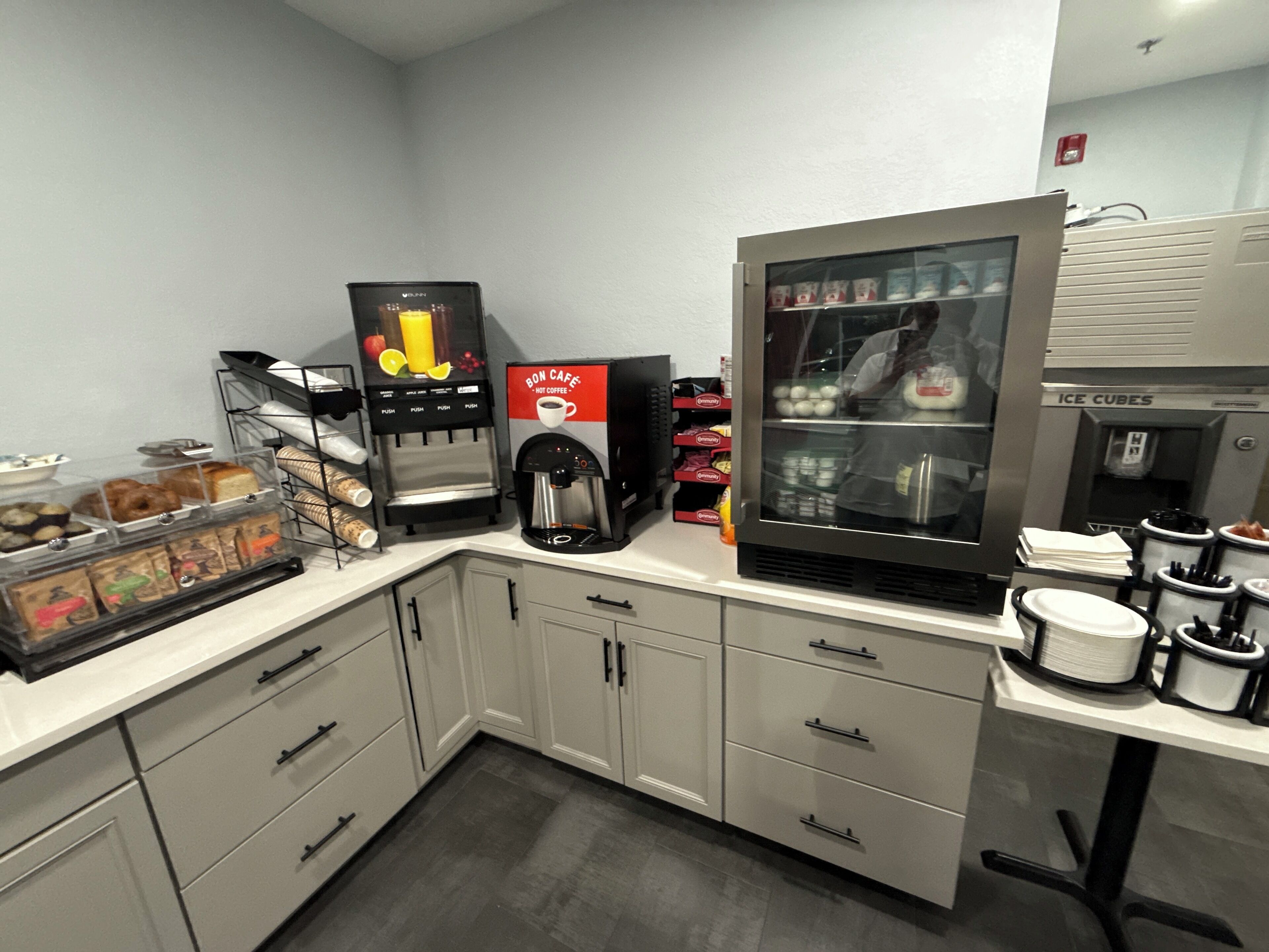 A kitchenette with a coffee machine, a refrigerator, and a coffee dispenser.