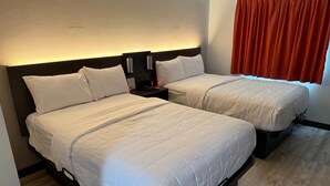 Two adjacent beds with white bedding, a nightstand with a lamp, and a red curtain.