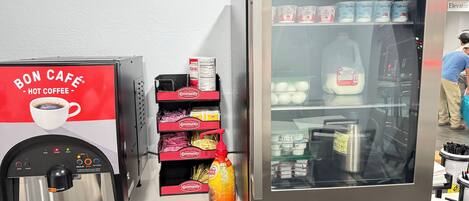 A coffee machine and a refrigerated display with various dairy products.
