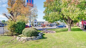 A hotel with a large sign, a parking lot, and a grassy area with trees. - Studio 6 Grand Prairie, TX (Grand Prairie)