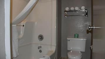 A bathroom with a bathtub, toilet, and a shelf with toiletries.