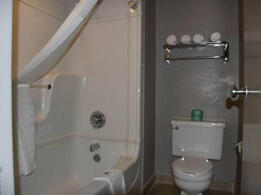 A bathroom with a bathtub, toilet, and a shelf with toiletries.