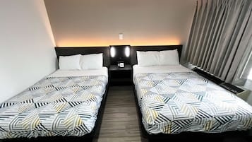A hotel room with two single beds, a nightstand with a phone, and a window with curtains.