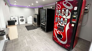Un cuarto de lavandería con una máquina expendedora de Coca-Cola, lavadoras y secadoras.