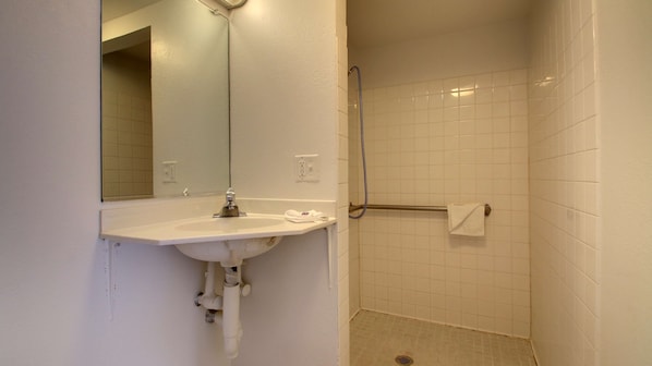 A bathroom with a sink, mirror, and shower.