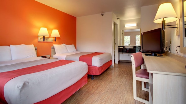 A hotel room with two beds, a desk with a chair, a television, and a bathroom visible through an open door. - Motel 6 Des Moines, IA - North (Des Moines)