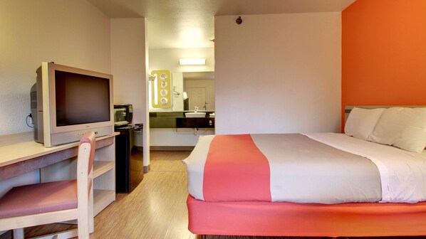 A hotel room with a bed, a desk with a television, a kitchenette, and a bathroom. - Motel 6 Des Moines, IA - North (Des Moines)