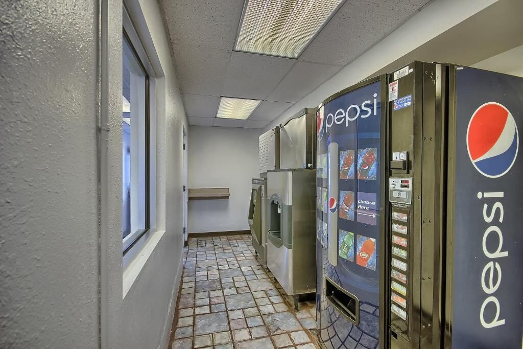 Un couloir avec un distributeur automatique de Pepsi et un réfrigérateur.