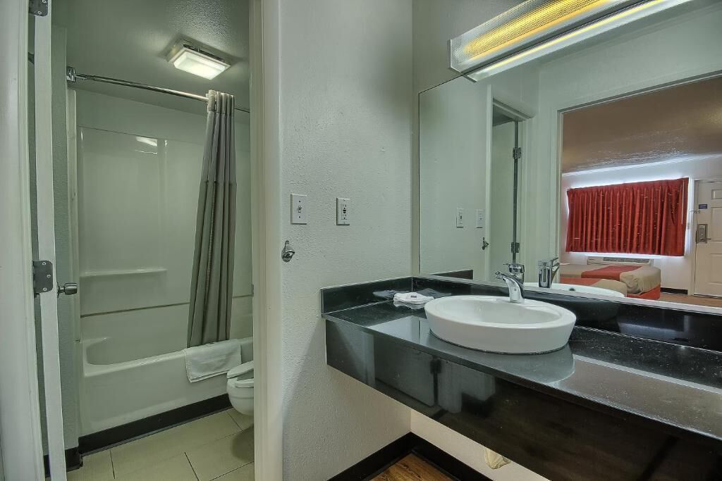 Une salle de bain moderne avec une douche à parois de verre, un lavabo blanc et un grand miroir.