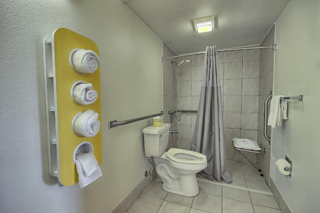 Une salle de bain comprenant des toilettes, une douche avec un rideau et un porte-serviettes avec des serviettes.