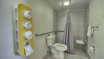 Une salle de bain comprenant des toilettes, une douche avec un rideau et un porte-serviettes avec des serviettes.