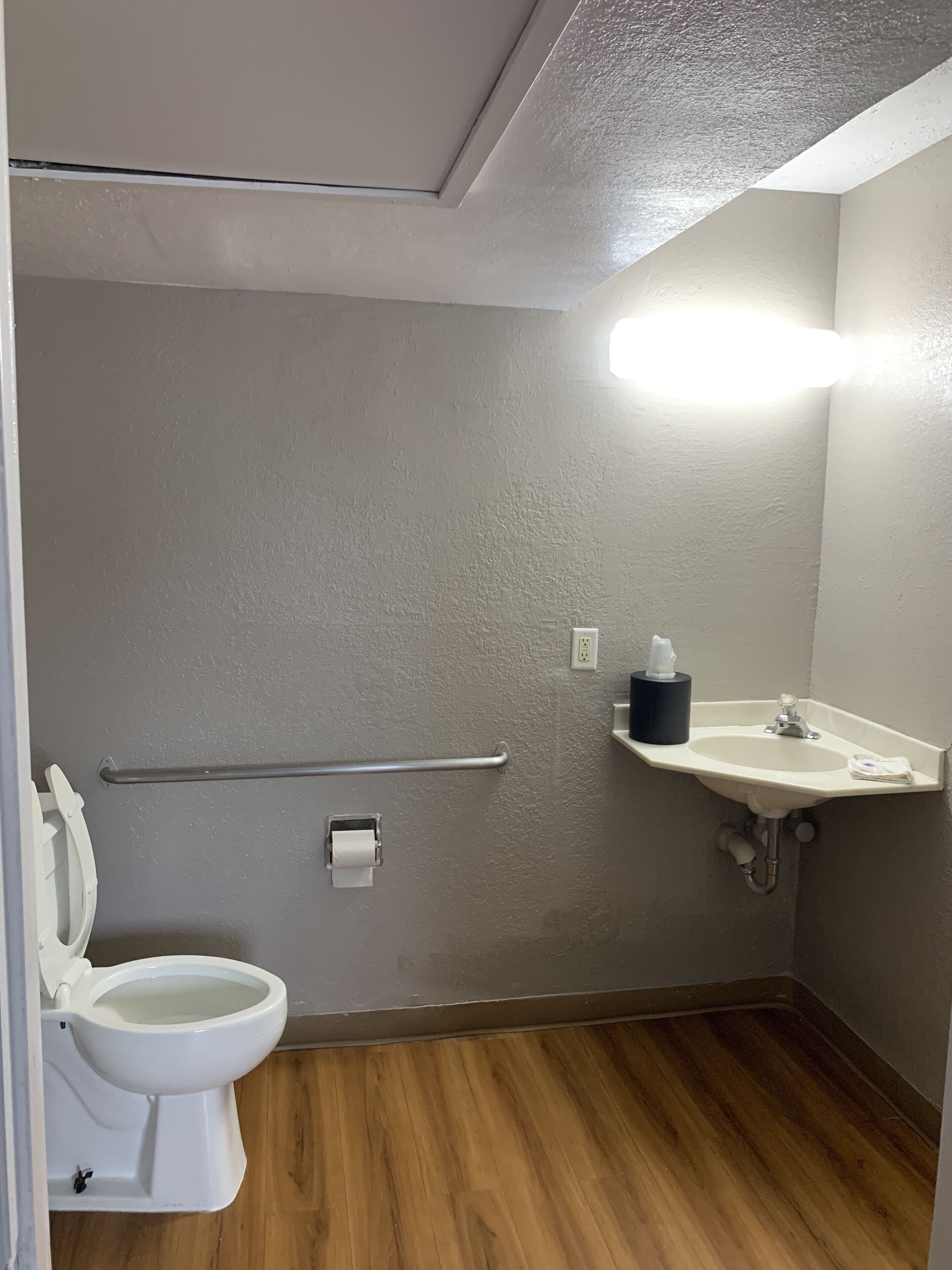 Un baño pequeño con inodoro, baranda, lavamanos y espejo.