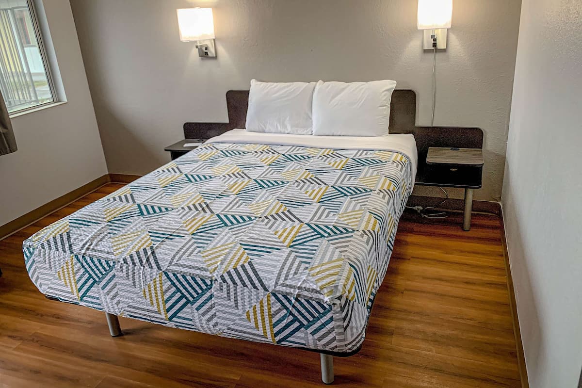 Ein Hotelzimmer mit einem Bett, zwei Nachttischen und zwei Wandlampen.