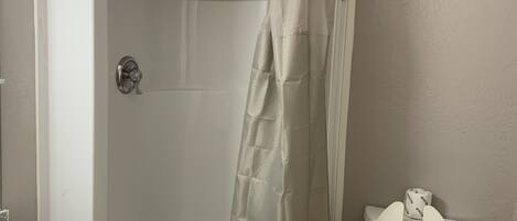 A bathroom with a glass-enclosed shower, a toilet, and a granite countertop.