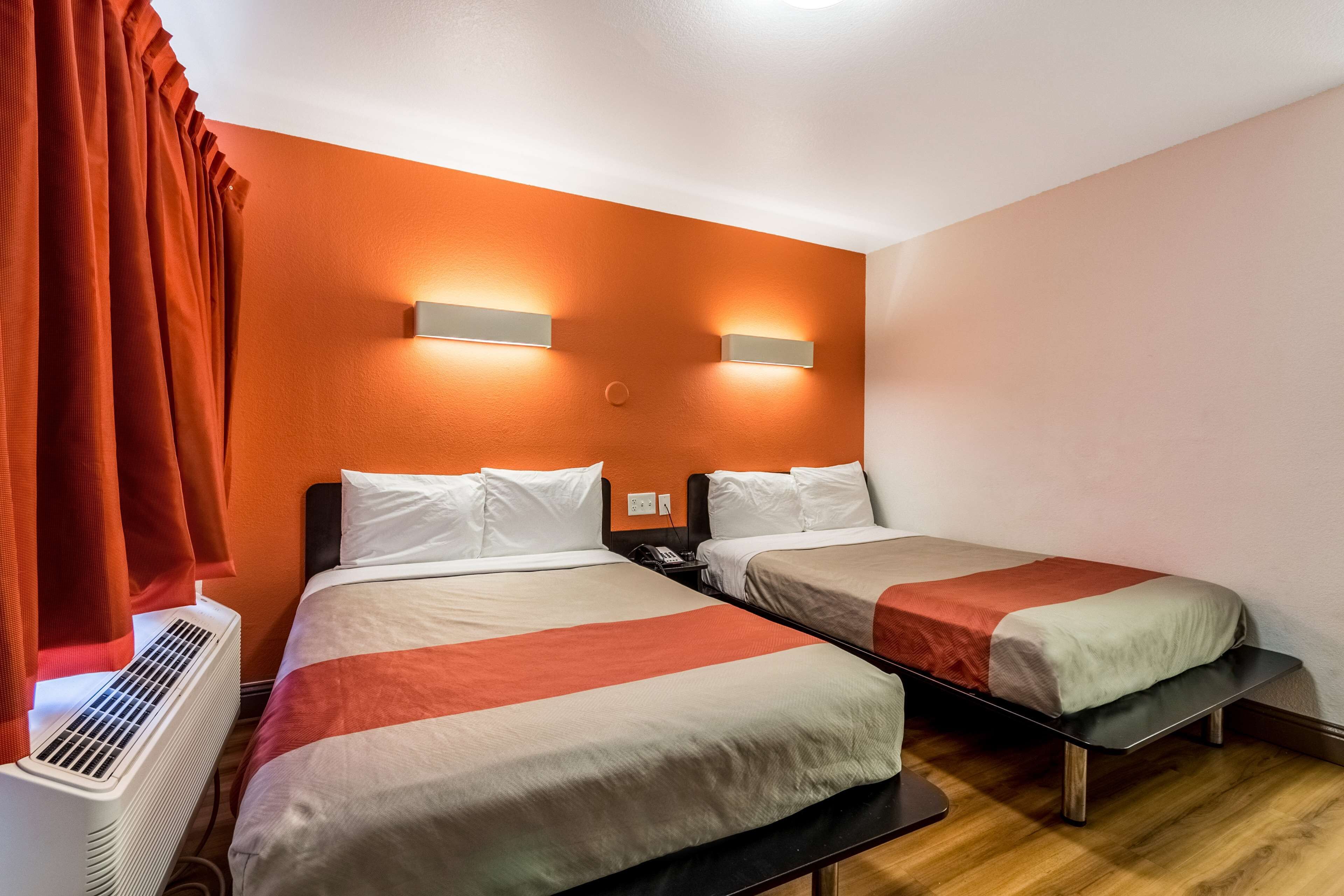 Habitación de hotel con dos camas, aire acondicionado y dos luces fijadas a la pared.