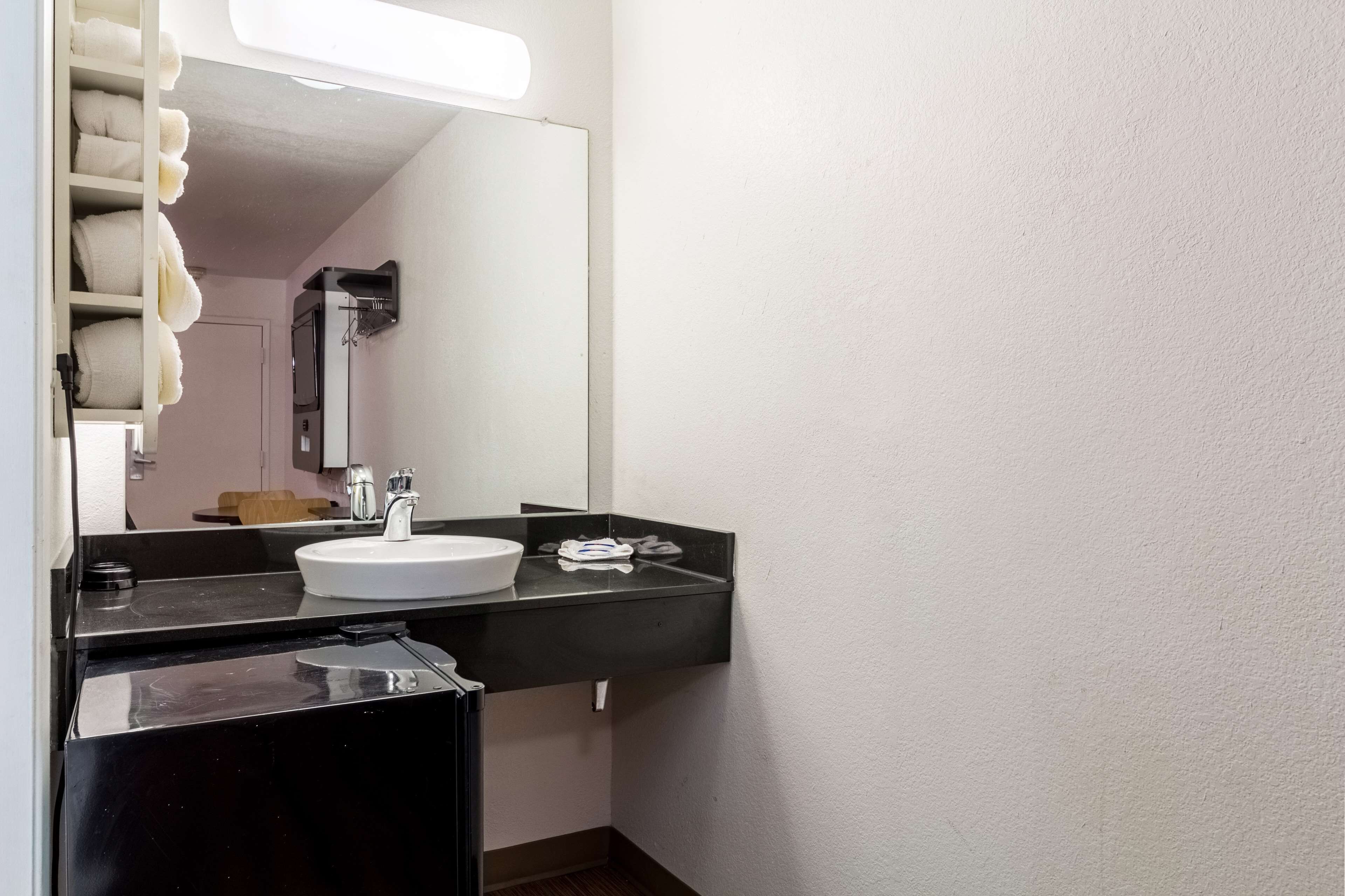 A bathroom with a white sink, black countertop, and a mirror.