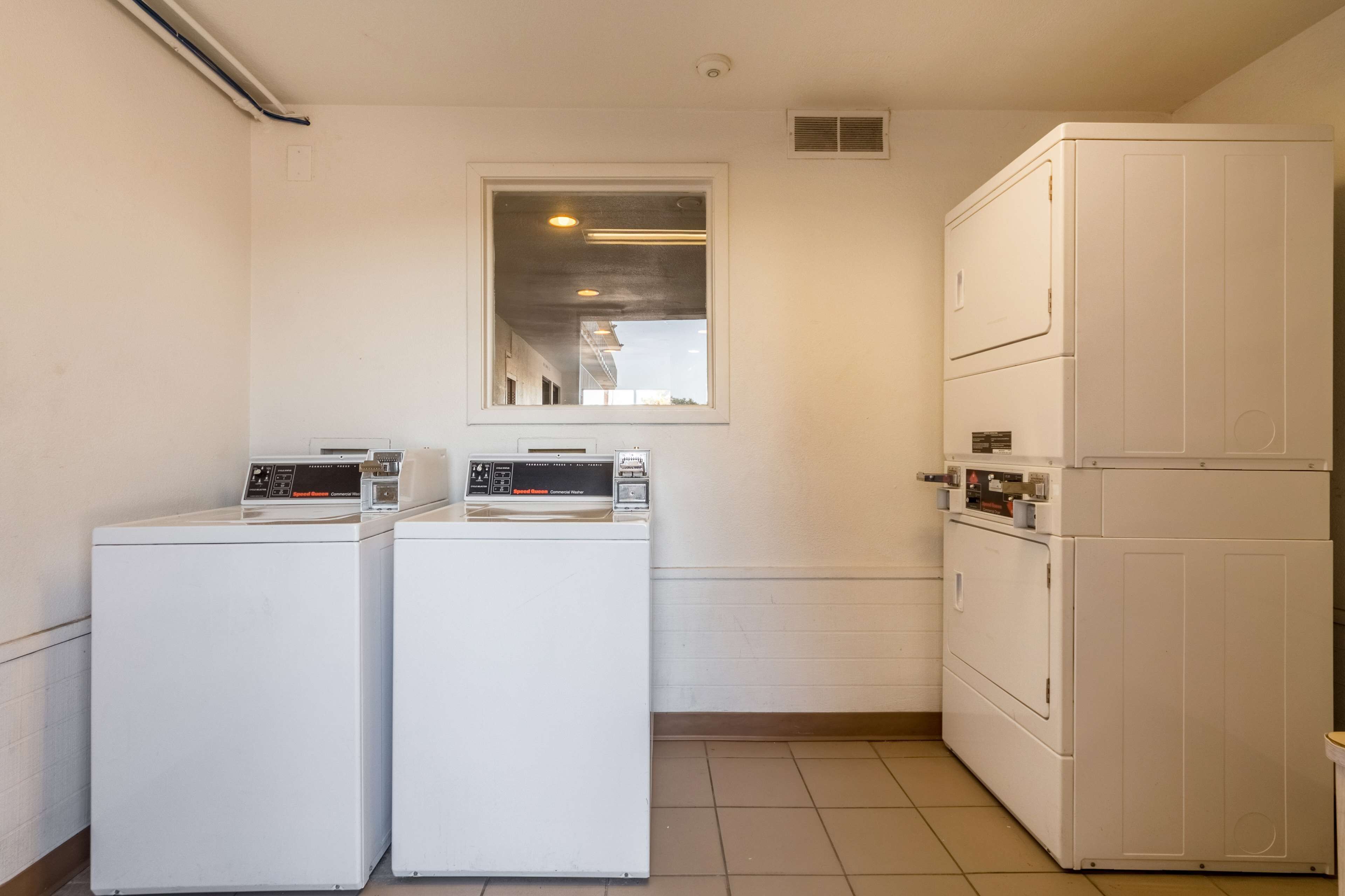 A laundry room with two front-loading washing machines and a stacked dryer.